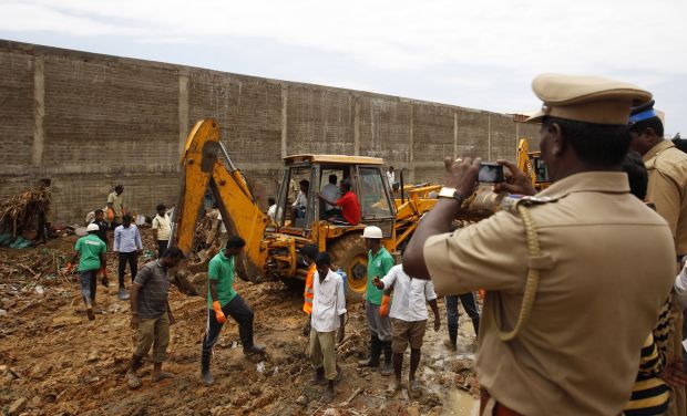 A policeman photographs the scene as workers clear the debris after the boundary wall of a warehouse collapsed on the outskirts of Chennai, on July 6, 2014. (Photo: AP) A policeman photographs the scene as workers clear the debris after the boundary wall of a warehouse collapsed on the outskirts of Chennai, on July 6, 2014. (Photo: AP)